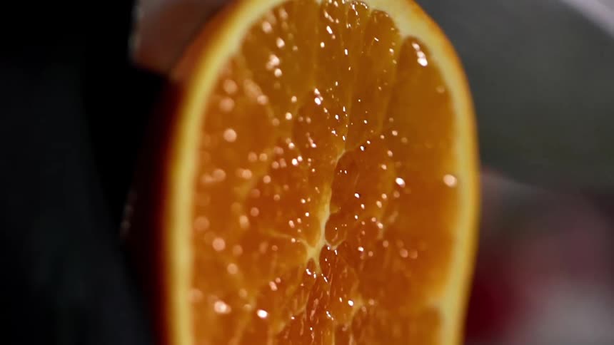 Close up of an orange being sliced by a knife