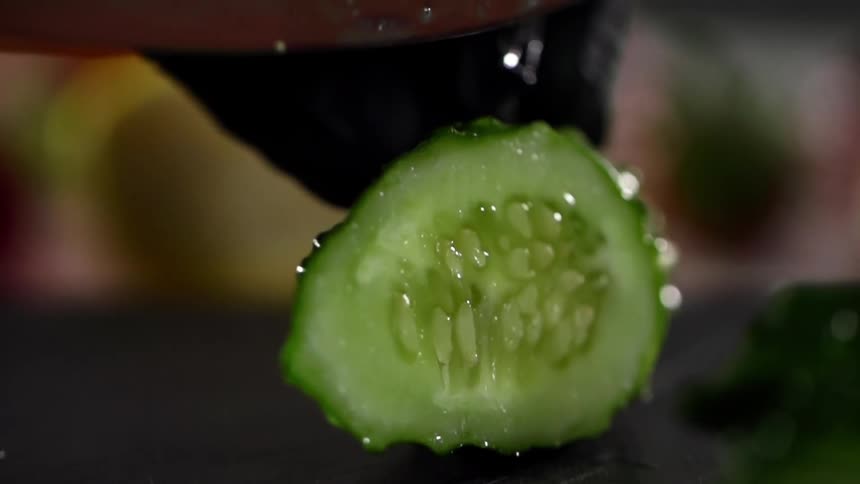 A person slowly cuts the cucumber