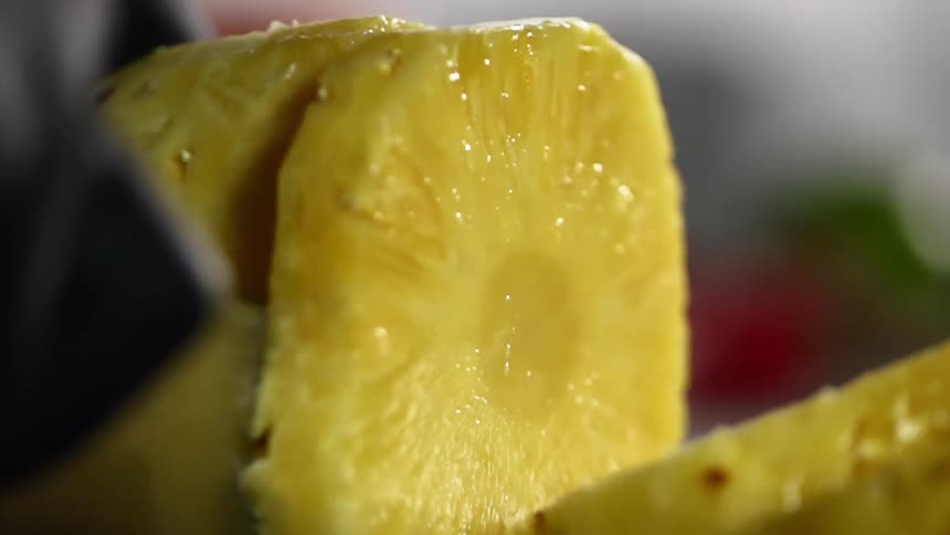 Close up of hands wearing black gloves cutting a pineapple