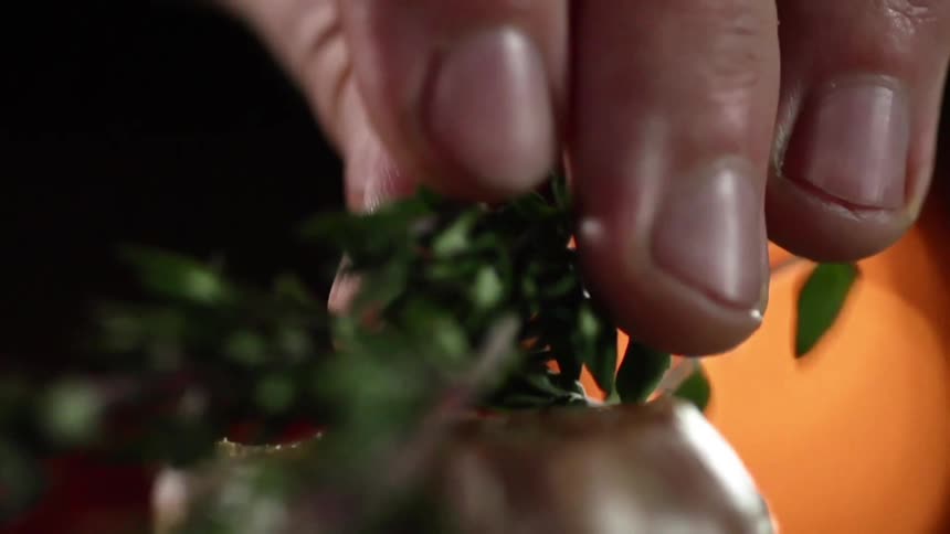 A man drops herbs down onto a wood pedestal in front of flames