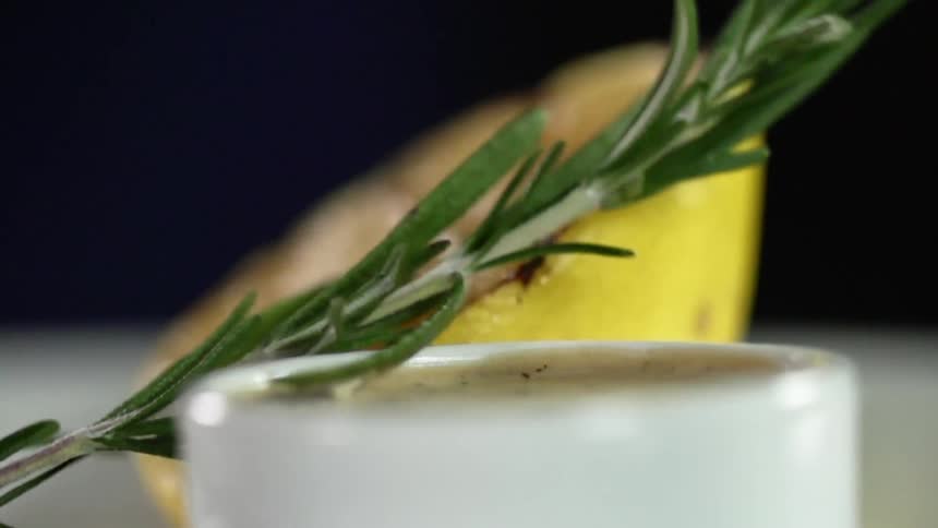 A green herb drops on a plate with a sauce bowl and food
