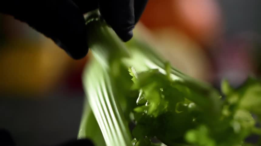 A person lifts a celery stalk