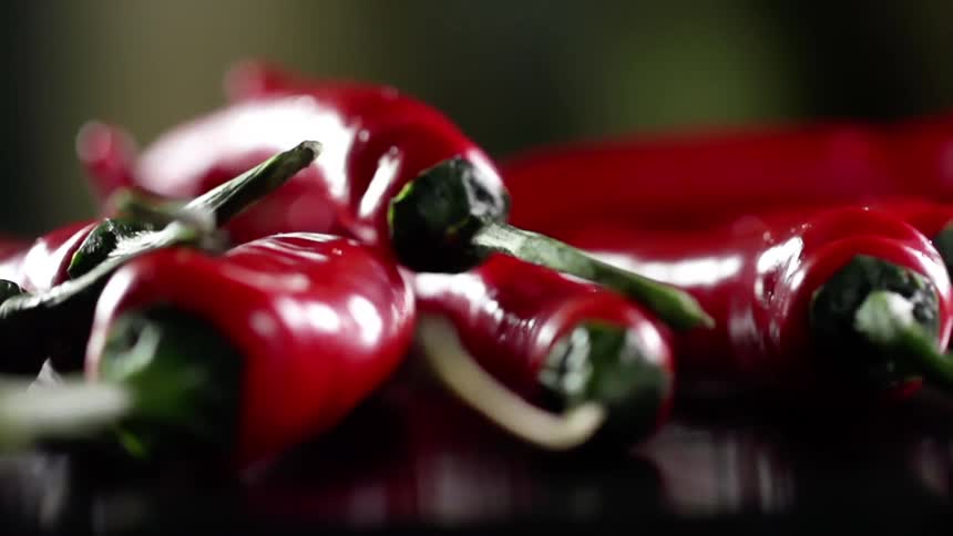 A long red pepper drops on top of other peppers