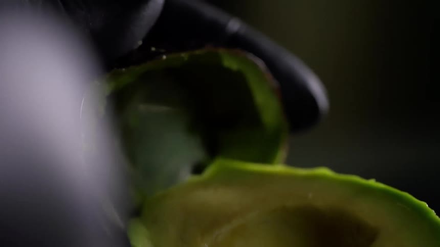 A person peeling the skin off of an avocado