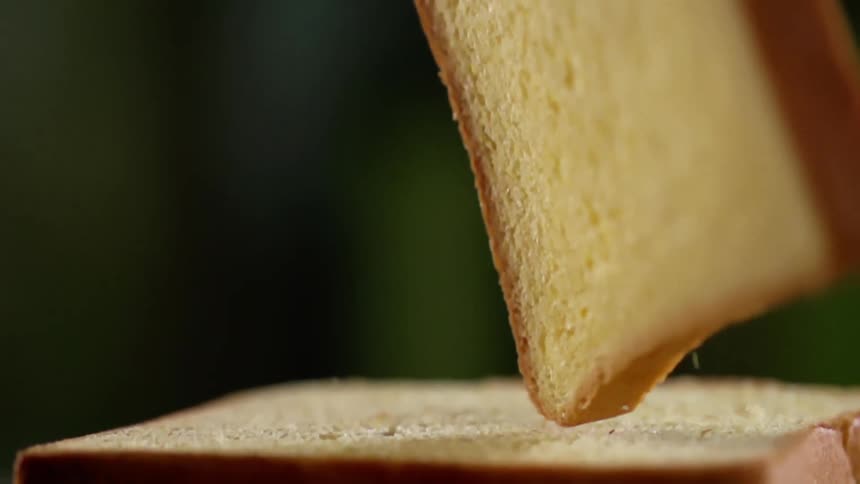 A piece of yellow bread falls and bounces until it falls over