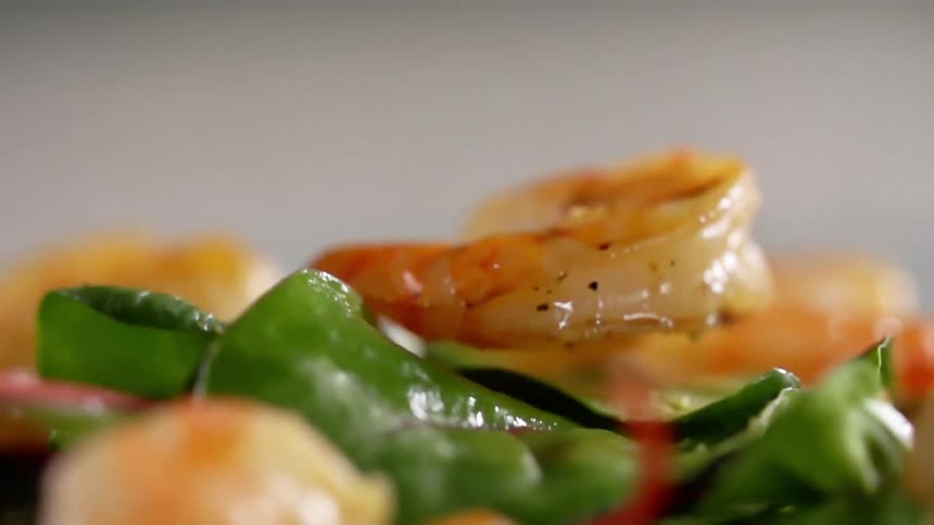 Shrimp falling on to a bed of spinach