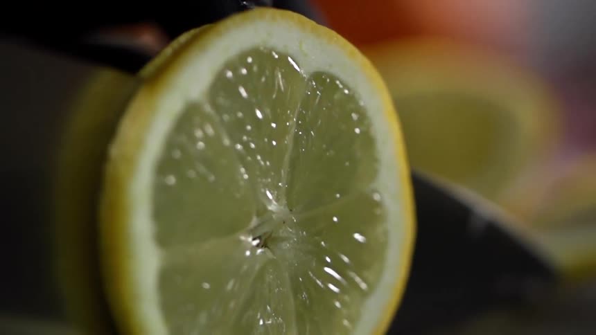 Close up of a lemon being sliced by a sharp knife