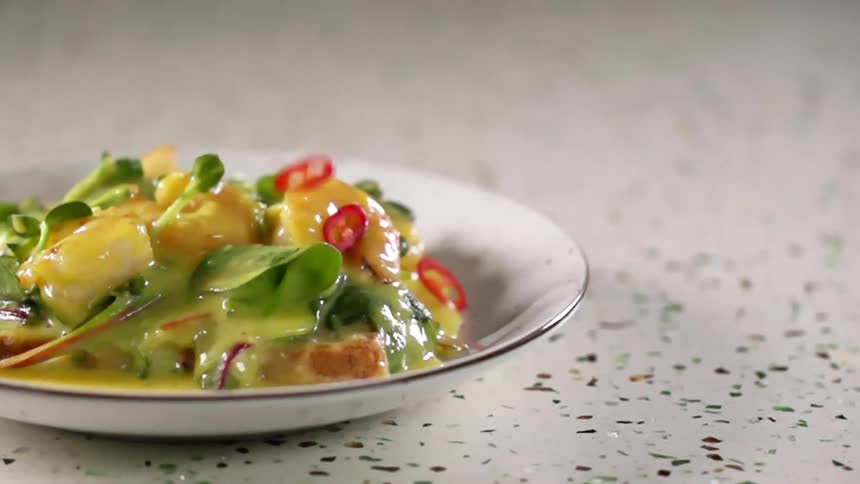 Salad with sauce on a white ceramic plate over the stone countertop of a kitchen