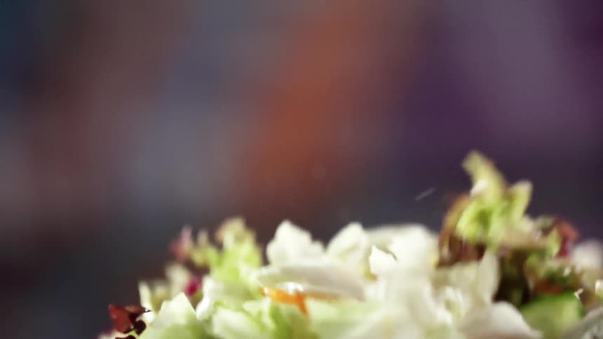 Black bowl of salad falls and bounces spilling out chopped produce