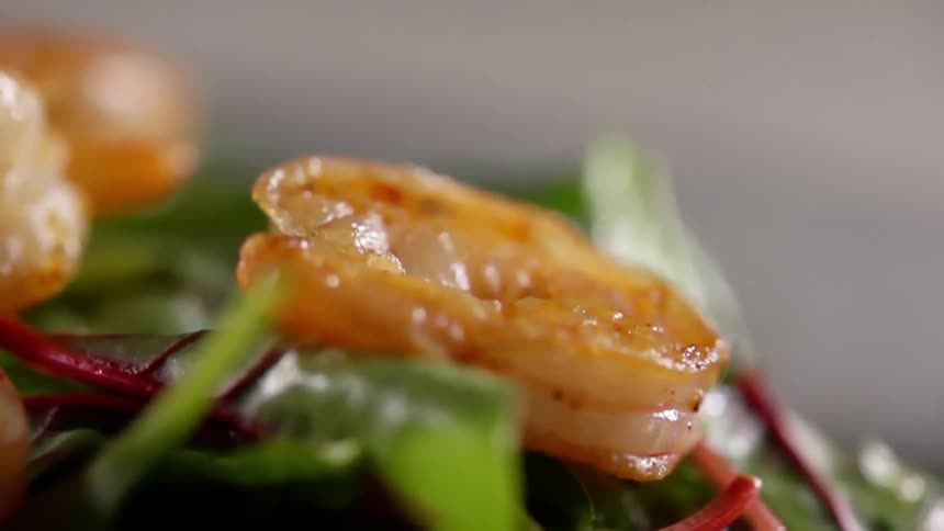 Close up of a shrimp falling on salad plate