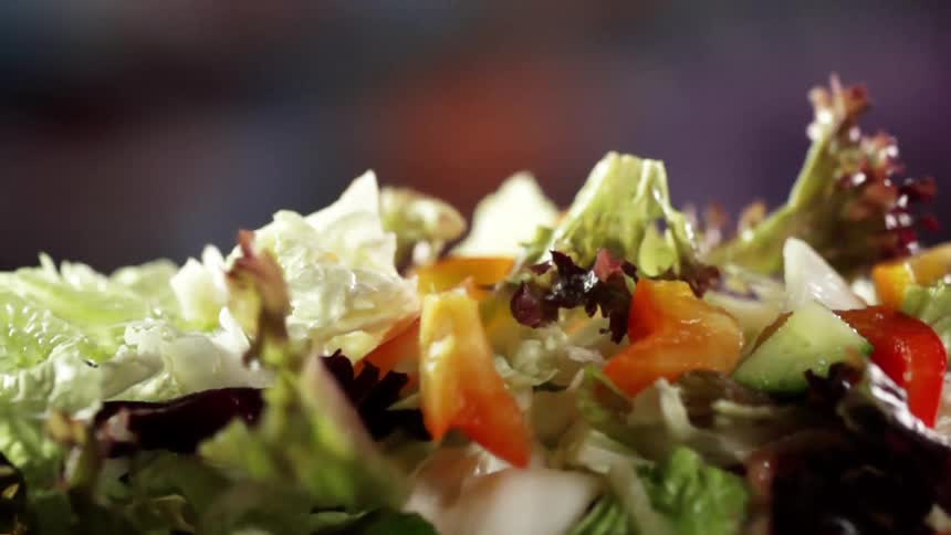 The ingredients of a salad falling to pile together on a plate