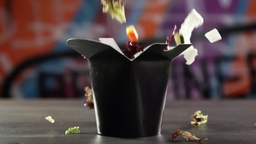 Various vegetables drop into a small cardboard meal box