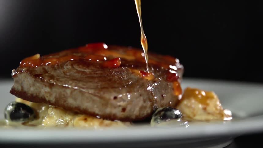 Sauce is being dripped on the plated meal