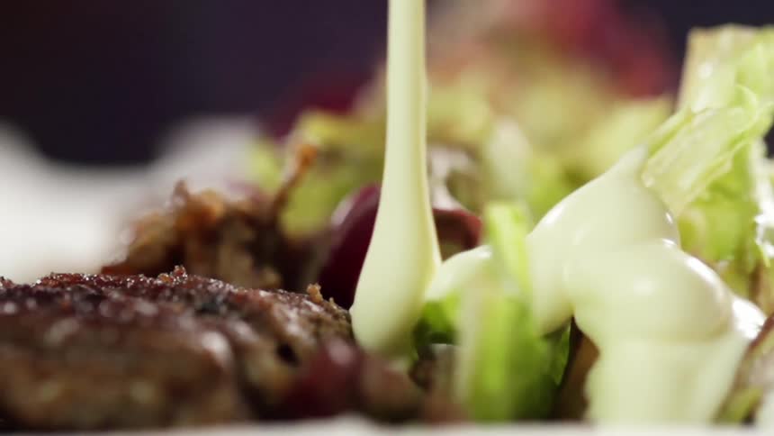 White sauce is poured on the lettuce and meat