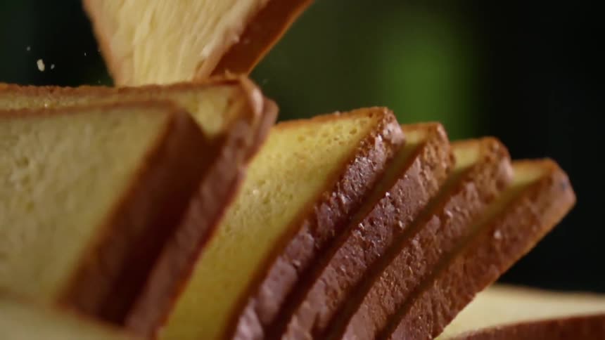 Close up of a hand wearing a black glove taking up a slice of bread