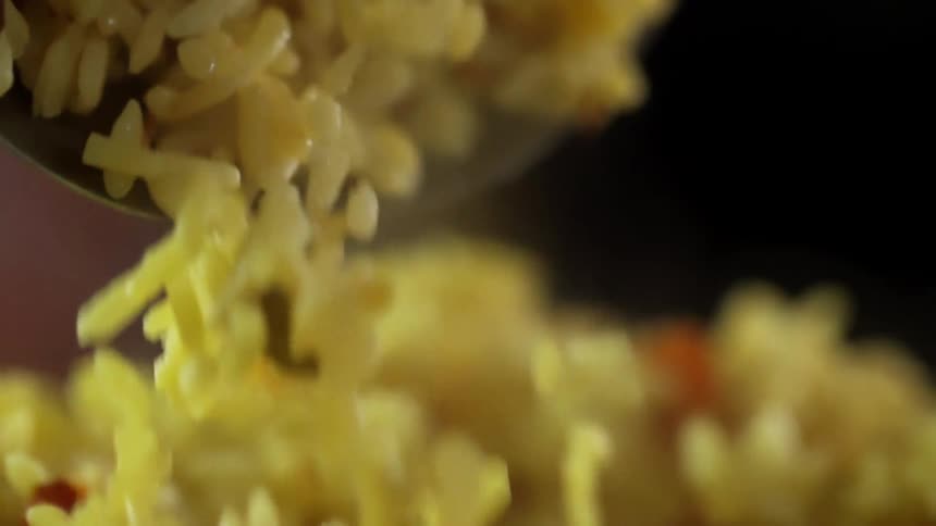 Close up of spoon stirring cooked yellow rice