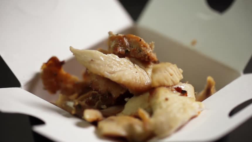 Fried pork pieces fall inside a cardboard takeout box