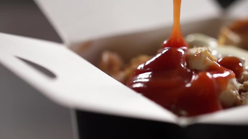 A red sauce pouring over meat in a meal box