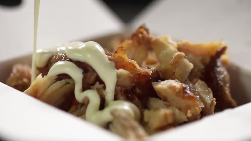 A cream sauce pours over meat chunks in a meal box