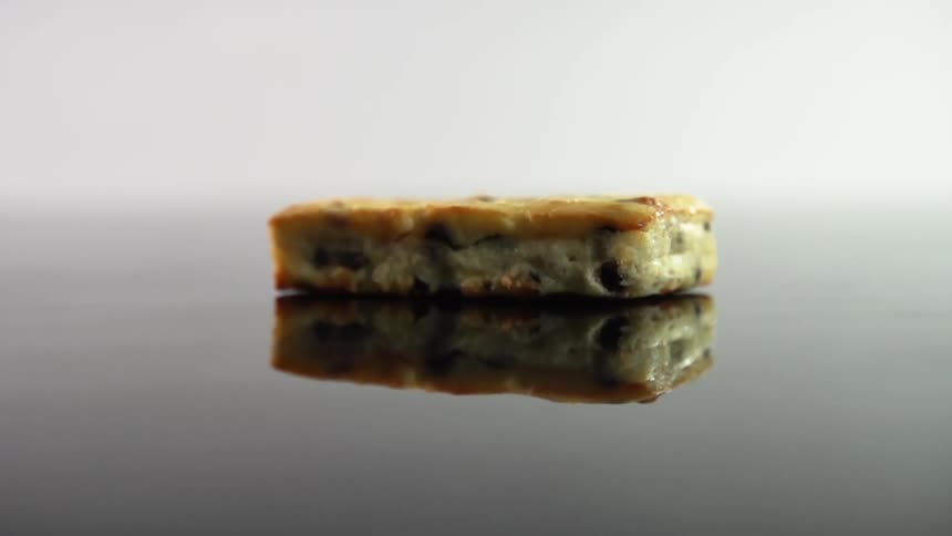 A small piece of cake drops onto a reflective table