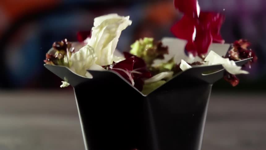 Various vegetables drop into a cardboard meal box