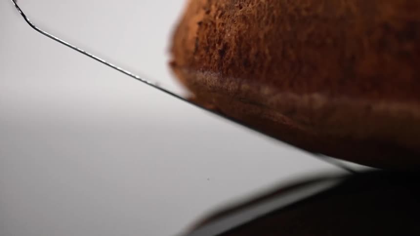 A spatula being removed from under a cake with a white background
