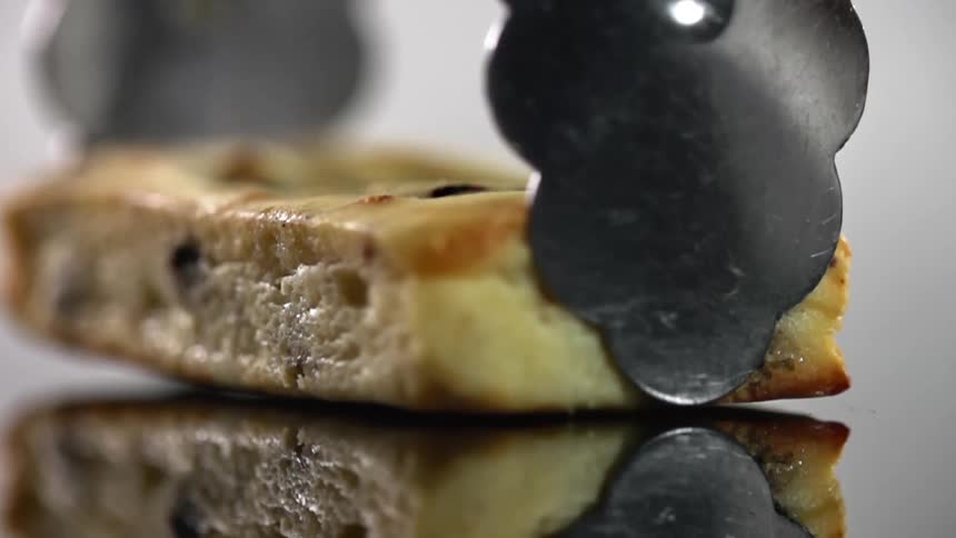 A piece of cake is placed with tongs