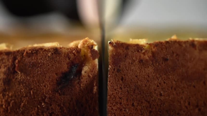 Close up of a hand cutting a cake in half