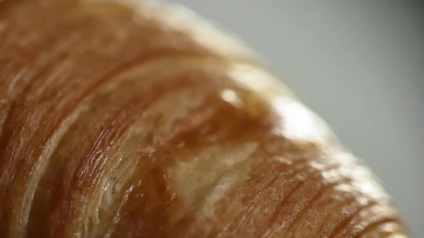 Light reflects off of a flaky croissant