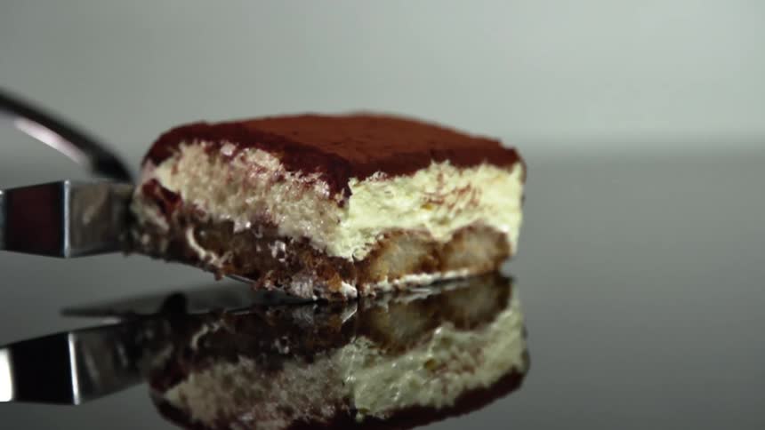 A piece of tiramisu is placed on a mirror surface