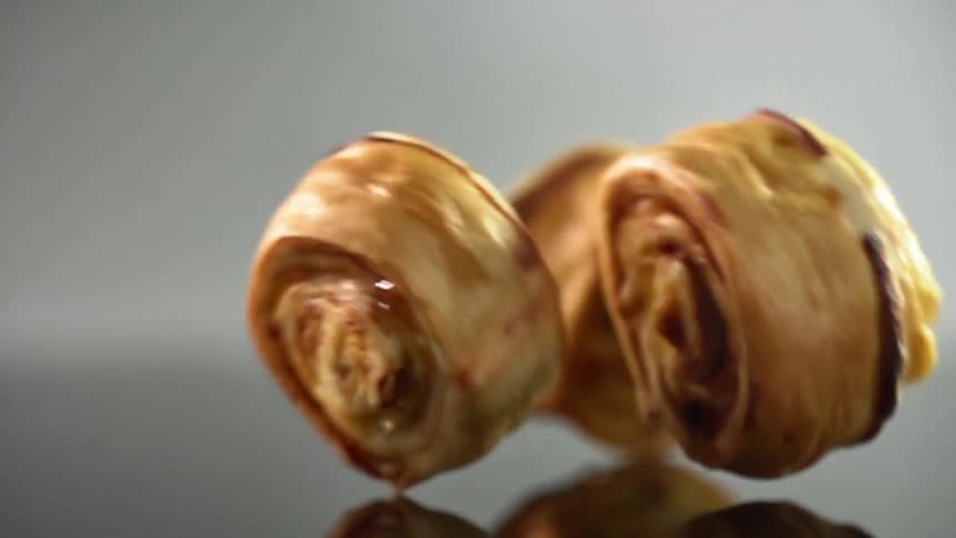 A person rolls pastries across a counter