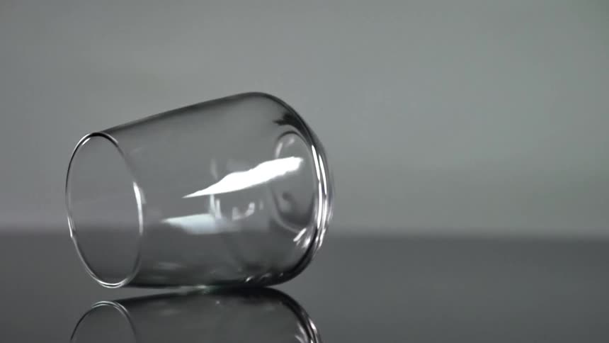 Stemless wine glass rotating on its side on a reflective counter
