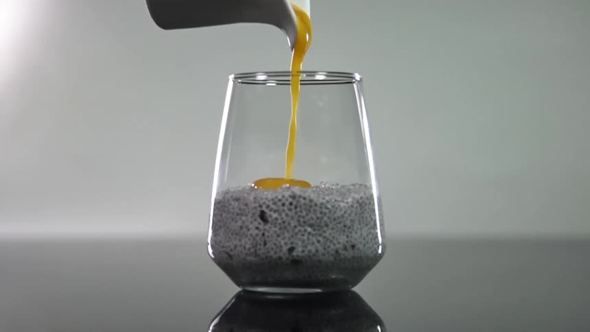 A small pitcher pours an amber sauce into a glass