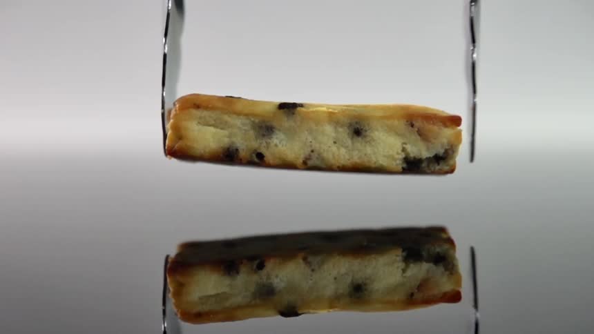 A pair of tongs lower a piece of cake and drops it on a table