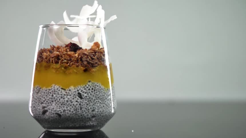 White strips of food drop into a glass filled with various types of food
