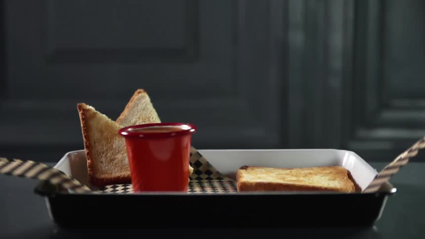 A tray with bread and a cup of sauce sits on a table