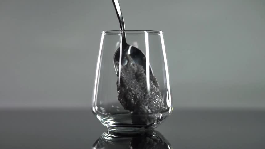 A spoon places a dollop of wet food into a glass