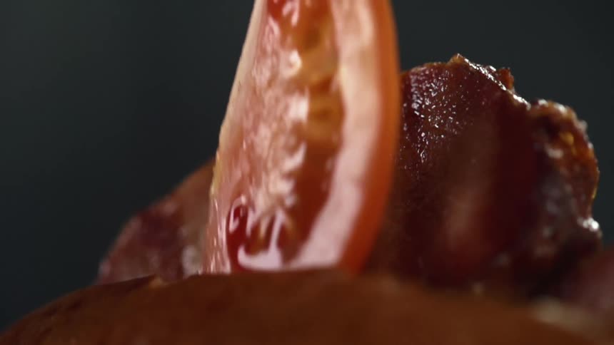 A piece of tomato falling in front of a piece of meat