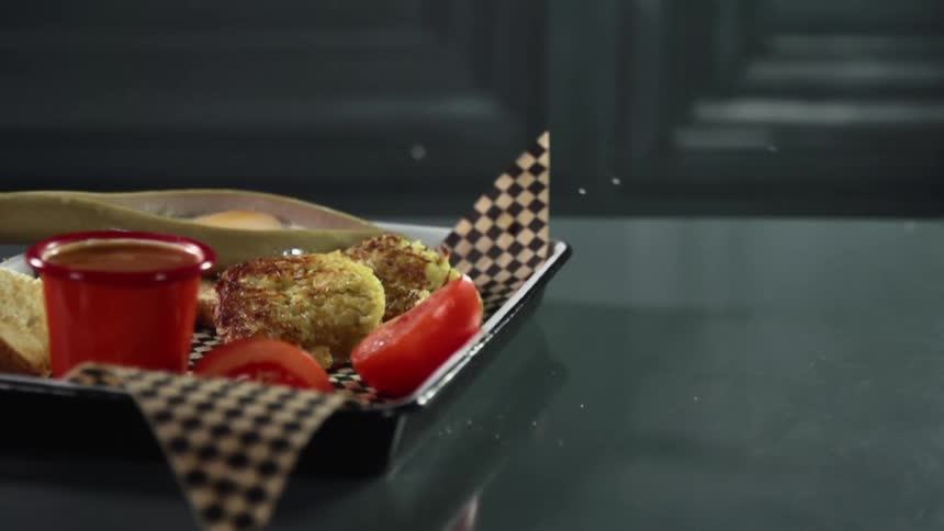 Sliced tomato falls into a tray filled with food in a kitchen counter top