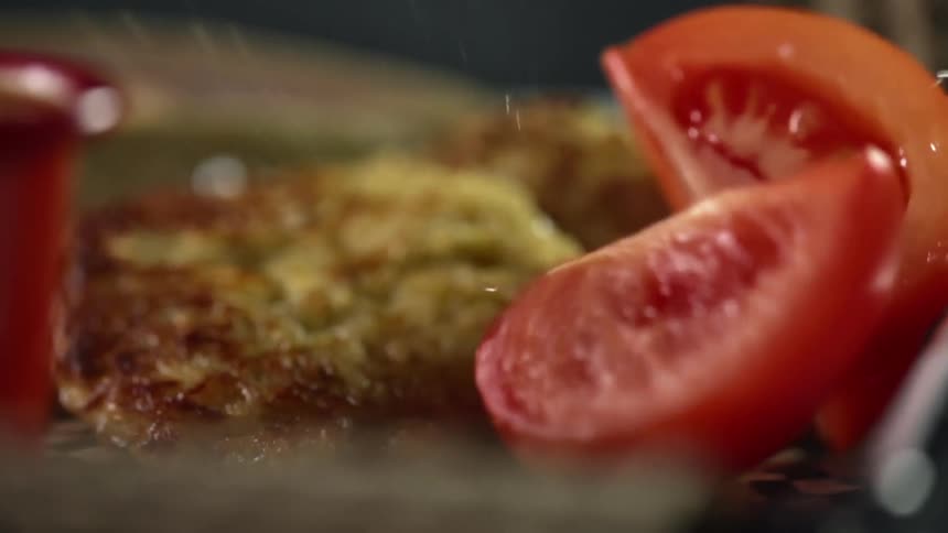 Tomatoes are dropped on a dish covered in paper with fried food on it