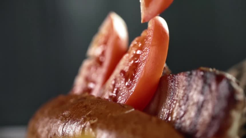 A tomato slice drops down onto a prepared meal