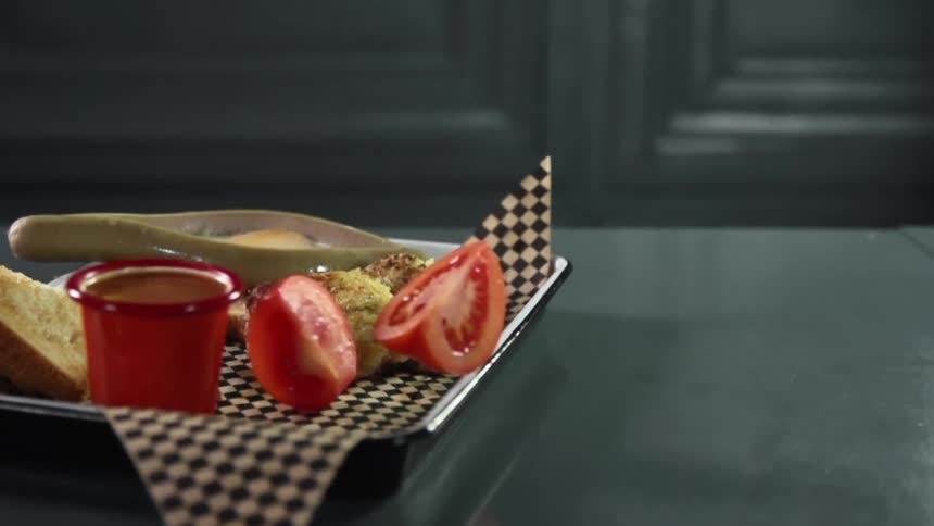 Tomato wedges drop onto paper lined tray near dipping sauce