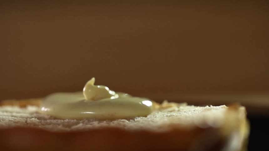 A half of hamburger bun has mayonnaise dripped onto it