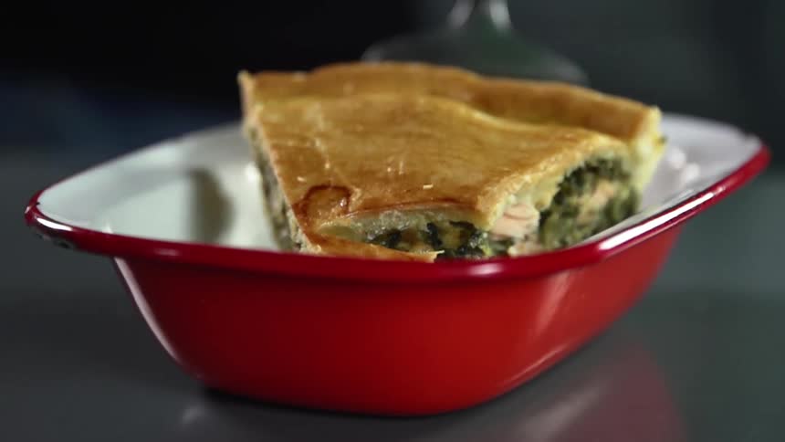 Slice of vegetarian quiche being placed inside a ceramic red bowl with a spatula