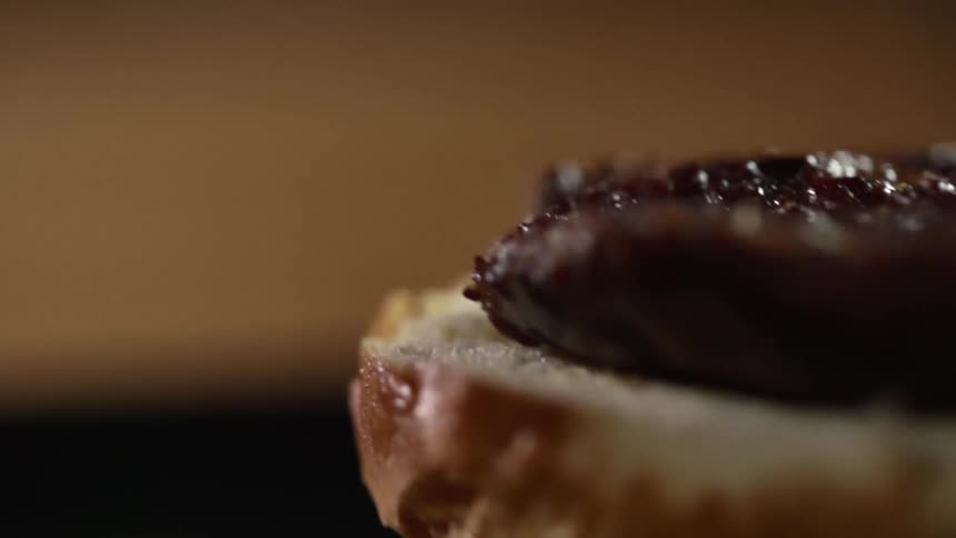A burger patty is dropped on a bun
