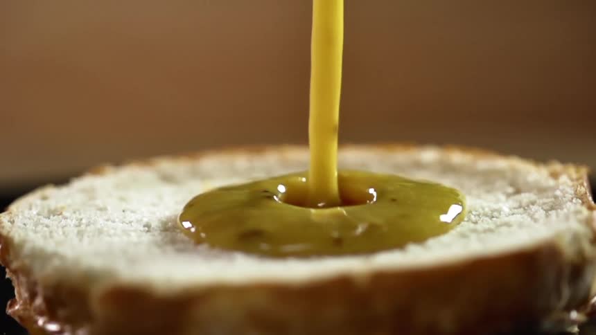 Sauce is poured onto a half of hamburger bun