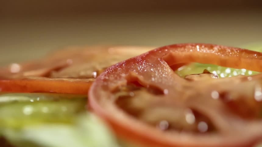 Two thin slices of tomato are dropped on top of a layer of sliced pickle spears