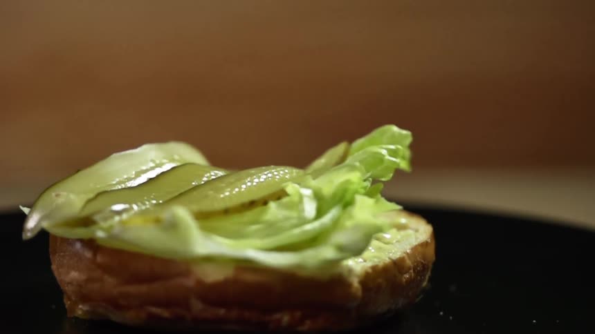 Three pickles slices drop on a bun with lettuce