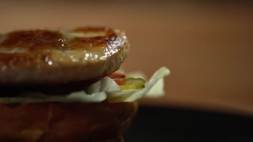 A chicken patty is dropped onto a bun with chopped tomato salsa