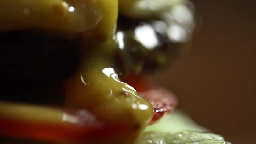 Running yellow sauce runs down the side of a hamburger
